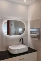 플루티드 타일과 유선형 거울의 모던 세면 공간